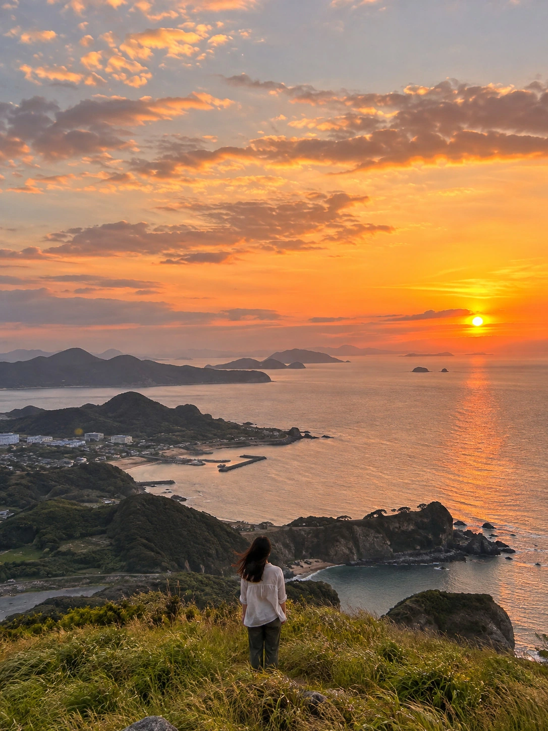 A traveler looking over the coastline at sunset